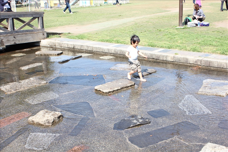 せせらぎで水遊びする幼児