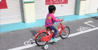 赤い補助輪付き自転車に乗る3歳の息子